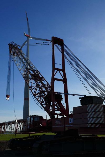 Korrordierende Arbeitssicherheit beim Schwerlastkran der Montage einer Windkraftanlage auf einem Industriegelände.